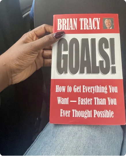 A hand holding the book Goals! by Brian Tracy