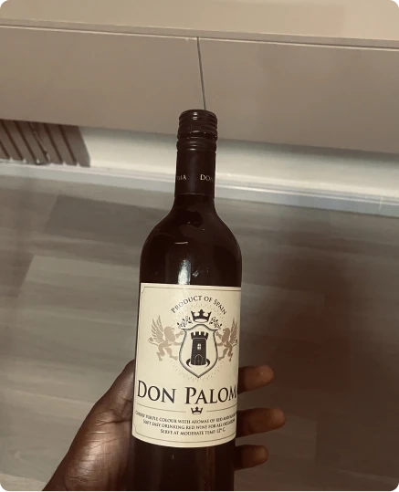 A hand holding a bottle of Don Paloma red wine