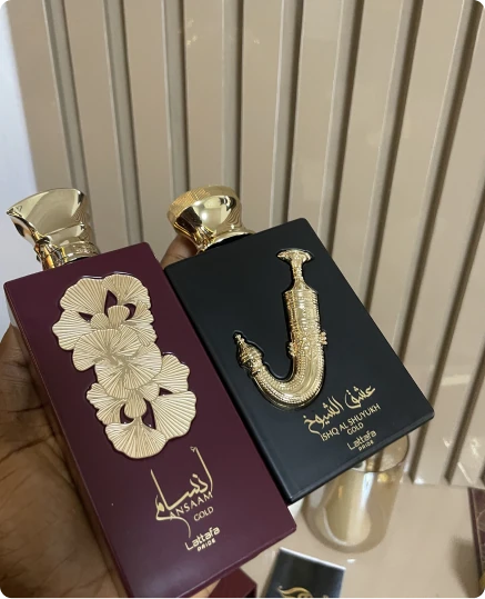 Two perfume bottles in maroon and black packaging with gold caps